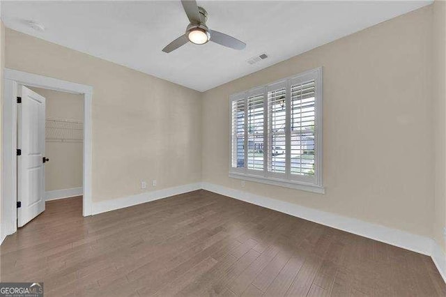 interior space featuring dark wood-style floors, visible vents, ceiling fan, and baseboards