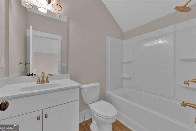 full bath with vanity, shower / bath combination, toilet, vaulted ceiling, and wood finished floors