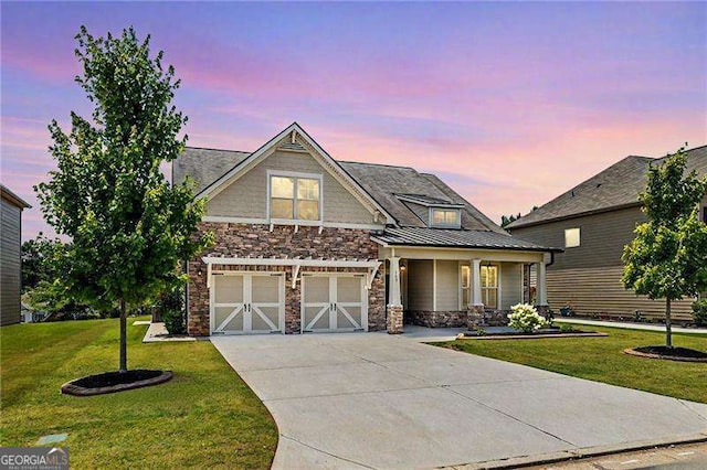craftsman-style home featuring a front lawn, driveway, stone siding, and an attached garage
