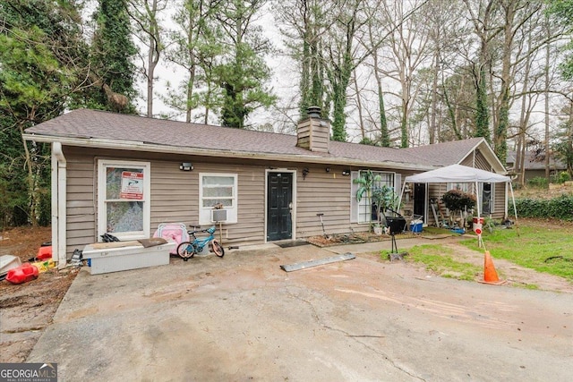 back of house with a chimney and a patio