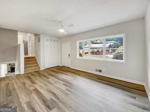 170 Pinehurst Dr, Stockbridge, GA 30281 - unfurnished living room featuring ceiling fan, wood finished floors, stairs, and a stone fireplace