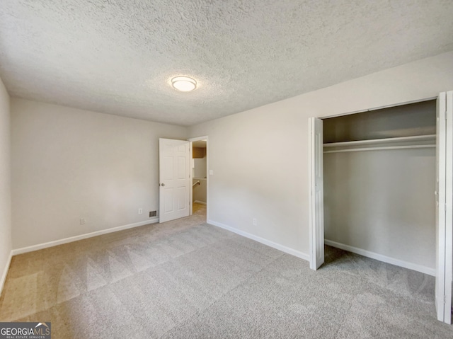 unfurnished bedroom with light carpet, a closet, and a textured ceiling