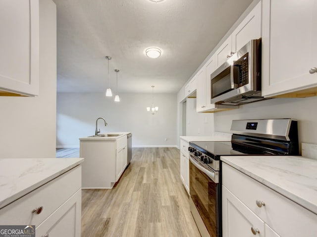 kitchen with sink, decorative light fixtures, stainless steel appliances, white cabinets, and light stone countertops