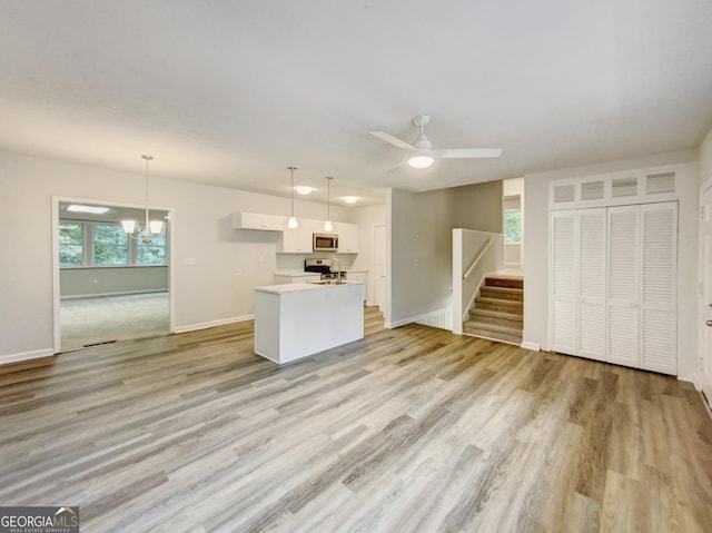 170 Pinehurst Dr, Stockbridge, GA 30281 - unfurnished living room with light wood finished floors, a ceiling fan, stairs, and a chandelier