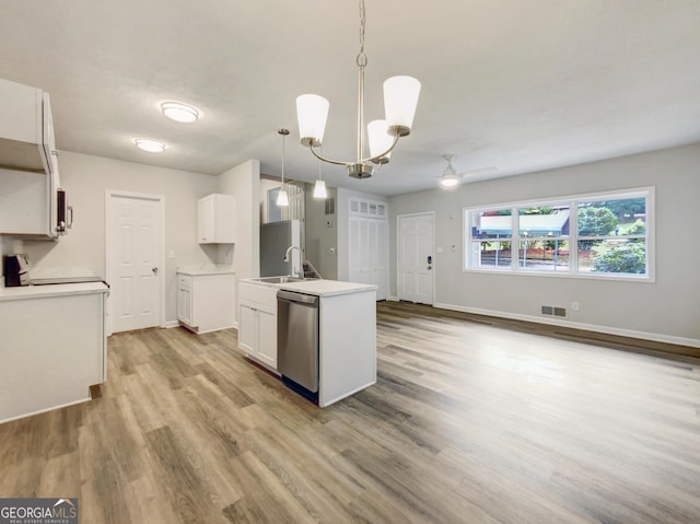 kitchen with white cabinetry, hanging light fixtures, light hardwood / wood-style flooring, sink, and stainless steel dishwasher