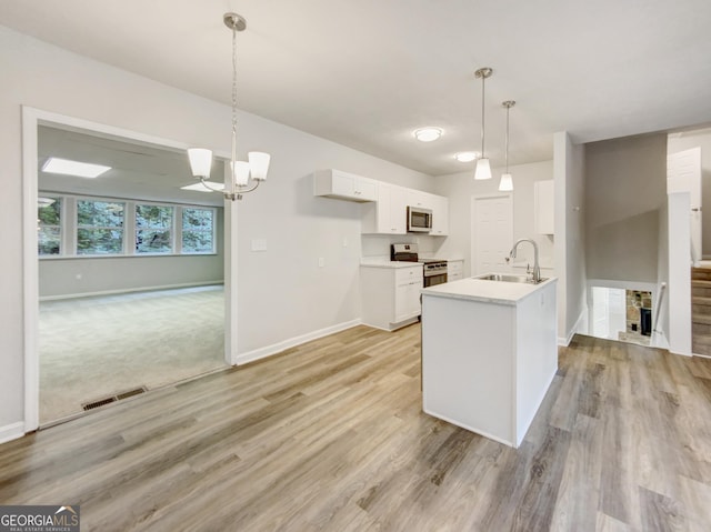 170 Pinehurst Dr, Stockbridge, GA 30281 - kitchen with appliances with stainless steel finishes, white cabinets, light wood finished floors, a chandelier, and light countertops