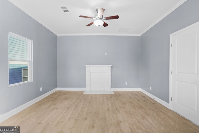 empty room with ornamental molding, light wood-type flooring, visible vents, and baseboards