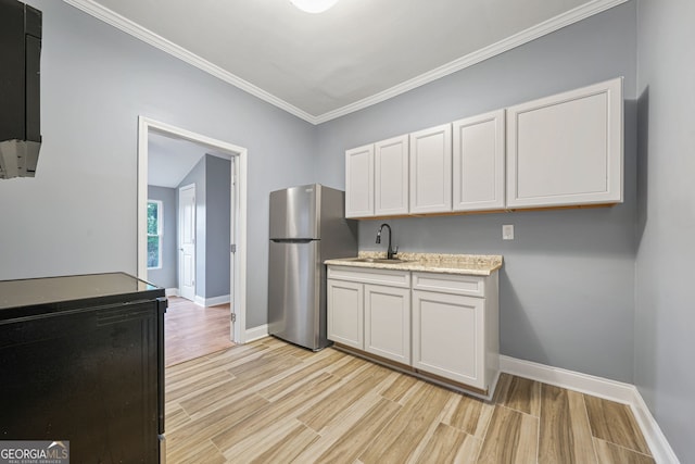 kitchen featuring light wood-type flooring, freestanding refrigerator, white cabinetry, and a sink