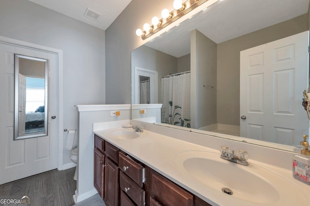 bathroom featuring double vanity, toilet, visible vents, and a sink