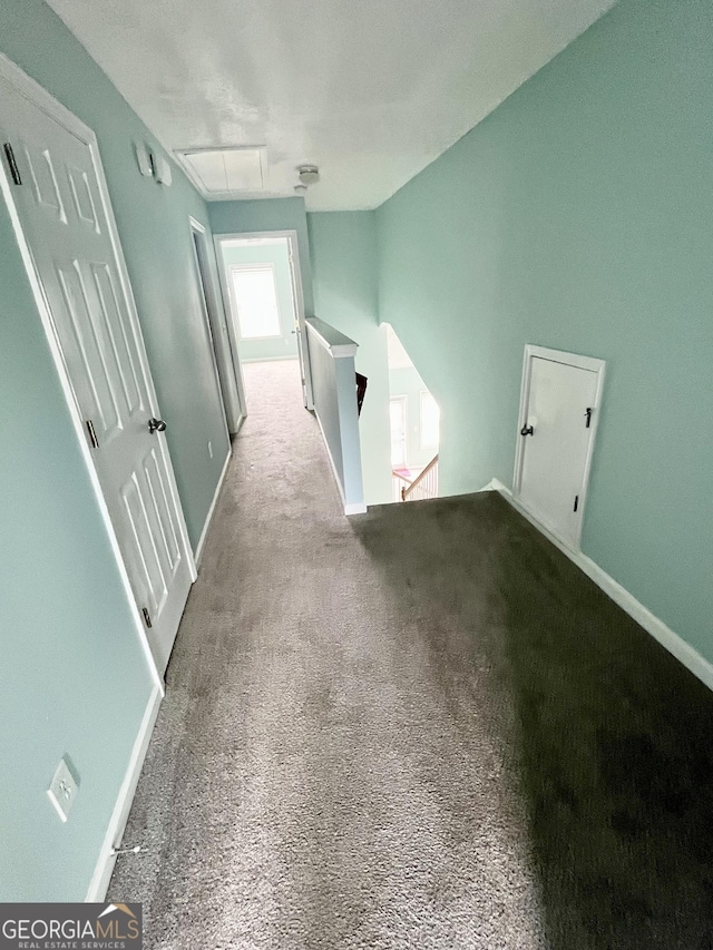 corridor with carpet flooring, baseboards, and an upstairs landing