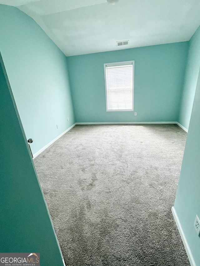 spare room with vaulted ceiling, baseboards, carpet flooring, and visible vents