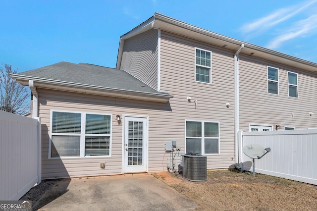 rear view of property with a patio, central AC unit, roof with shingles, and fence