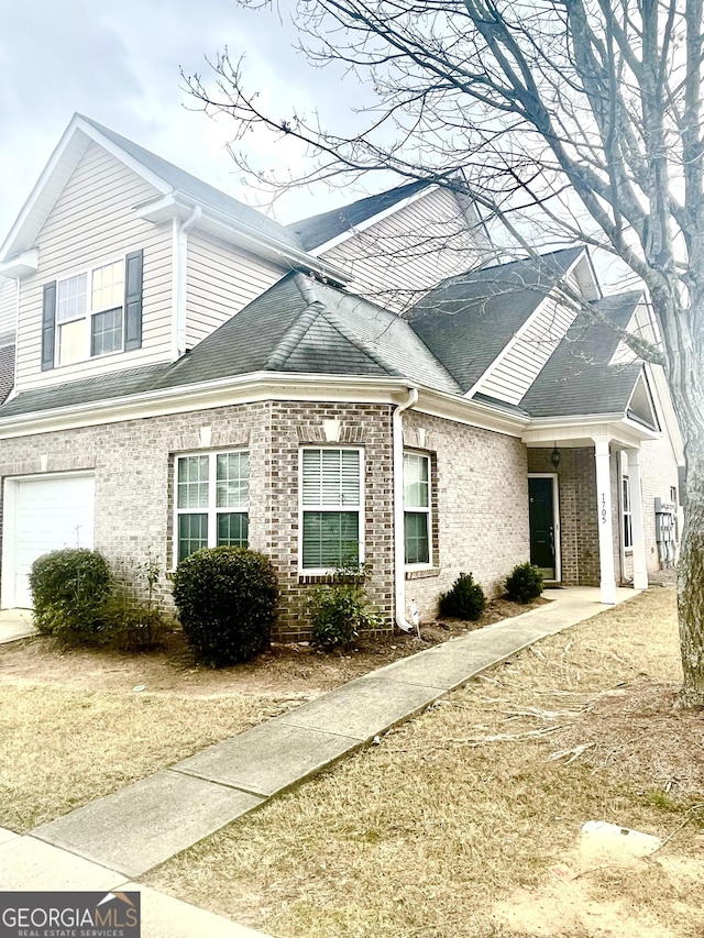 view of side of home with a garage, roof with shingles, and brick siding