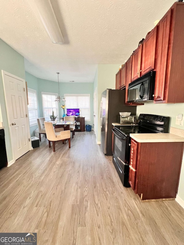 kitchen with light hardwood / wood-style floors, hanging light fixtures, a textured ceiling, and black appliances