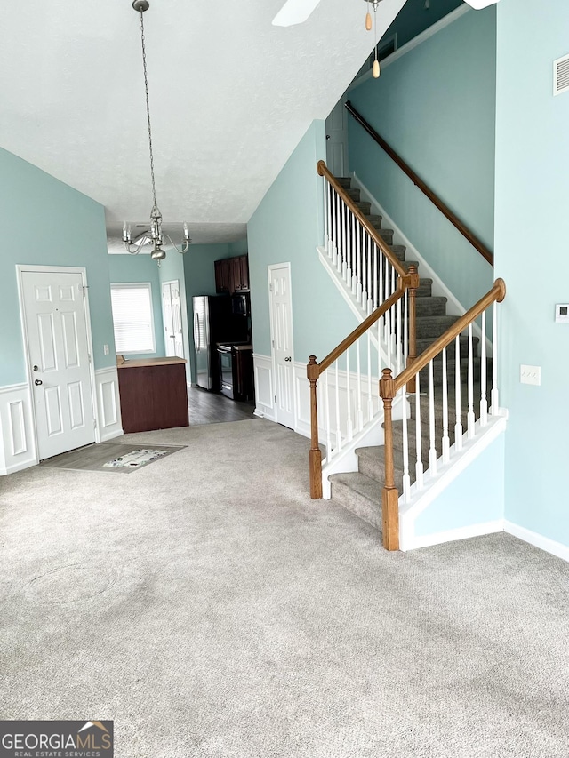 unfurnished living room with stairway, a wainscoted wall, carpet flooring, and visible vents