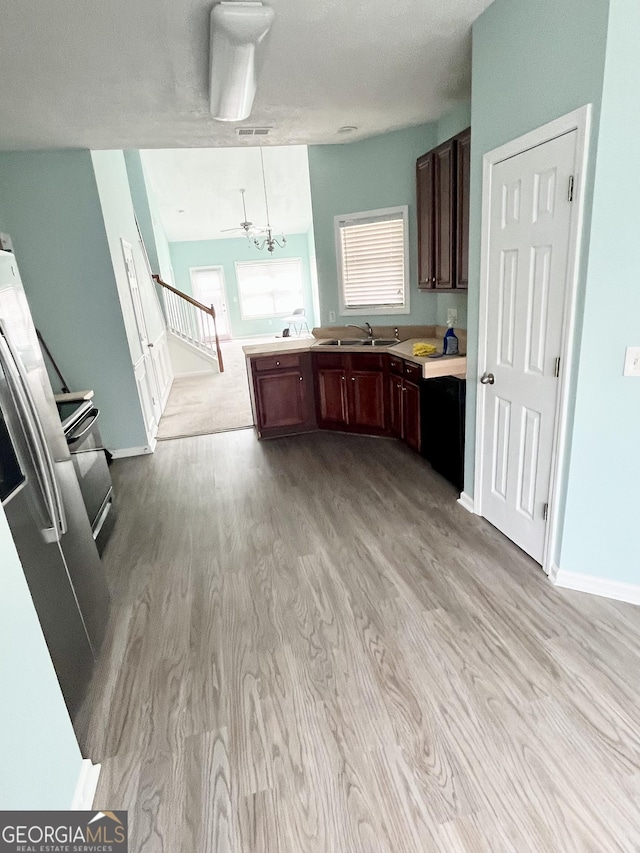 kitchen with light countertops, a peninsula, a sink, and light wood-type flooring