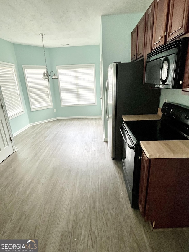 kitchen featuring an inviting chandelier, baseboards, black appliances, and light wood-style flooring