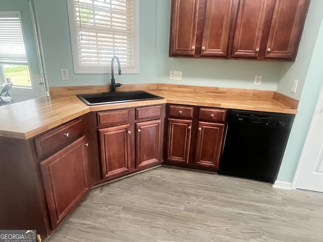 kitchen featuring black dishwasher, wooden counters, and a sink