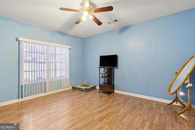 unfurnished room featuring ceiling fan, light hardwood / wood-style flooring, and a textured ceiling