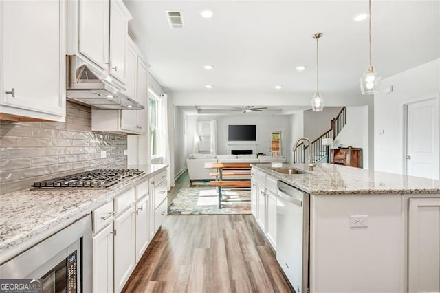 kitchen with appliances with stainless steel finishes, hanging light fixtures, an island with sink, white cabinets, and sink