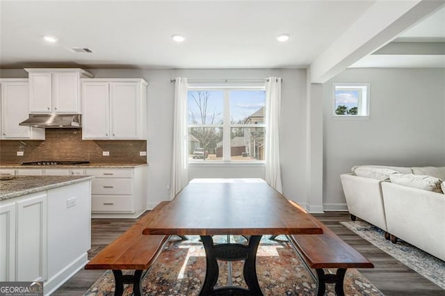 kitchen featuring backsplash, black gas stovetop, dark hardwood / wood-style flooring, white cabinets, and light stone countertops