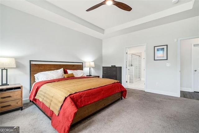 bedroom with a tray ceiling, ceiling fan, carpet, and connected bathroom