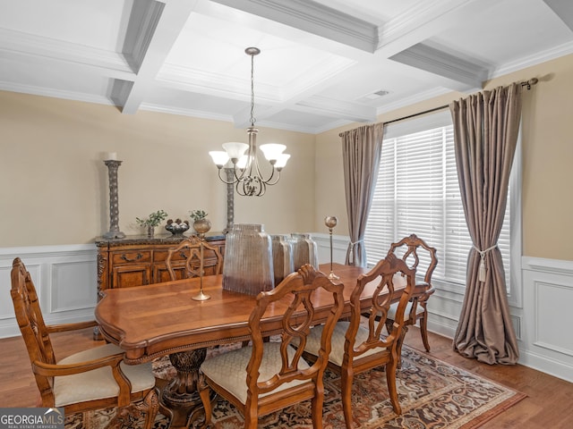 dining space featuring beam ceiling, hardwood / wood-style flooring, coffered ceiling, ornamental molding, and an inviting chandelier