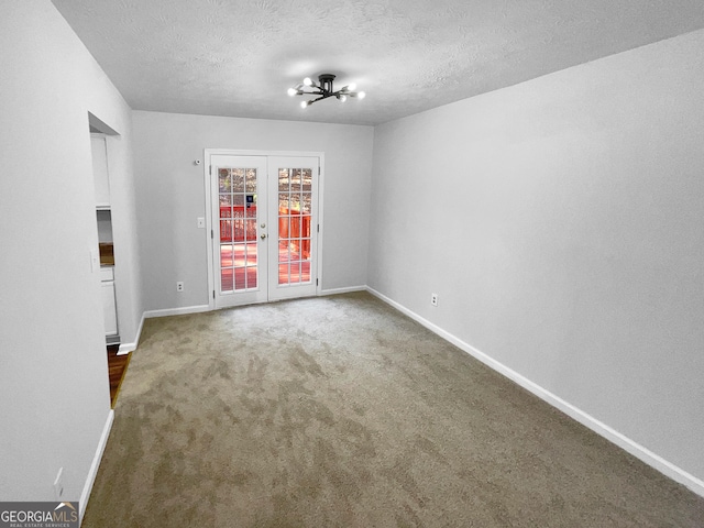 spare room with carpet, french doors, and a textured ceiling