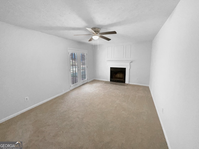 unfurnished living room with a textured ceiling, ceiling fan, french doors, and light colored carpet