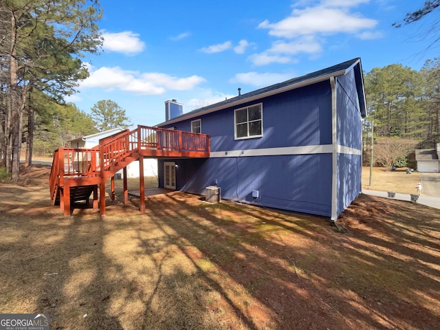 rear view of property with a wooden deck and a lawn