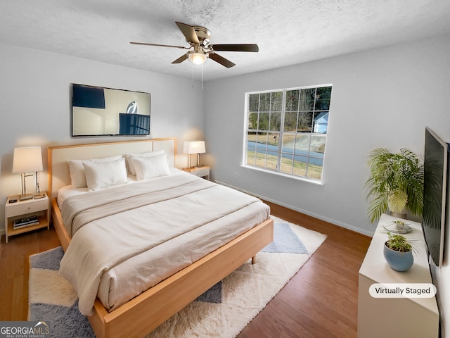 bedroom featuring hardwood / wood-style flooring, ceiling fan, and a textured ceiling