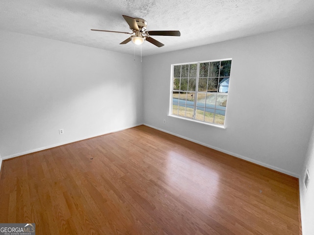 empty room with hardwood / wood-style flooring, ceiling fan, and a textured ceiling