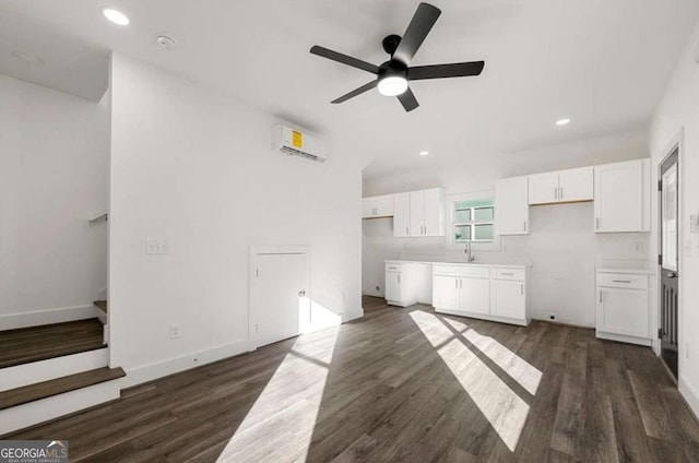 unfurnished living room with sink, ceiling fan, a wall mounted air conditioner, and dark hardwood / wood-style flooring