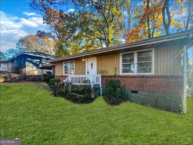 ranch-style house with a front yard, crawl space, brick siding, and covered porch