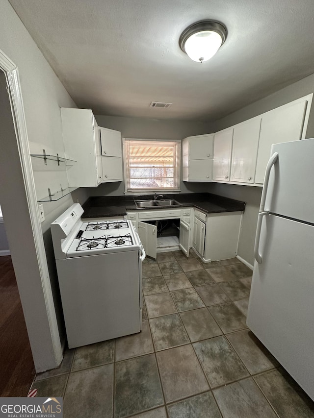 kitchen featuring white appliances, dark countertops, visible vents, and white cabinets