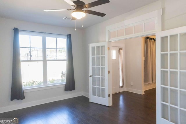 unfurnished room featuring plenty of natural light, dark wood-style floors, and baseboards