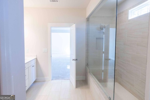 bathroom with walk in shower, tile patterned flooring, vanity, baseboards, and visible vents