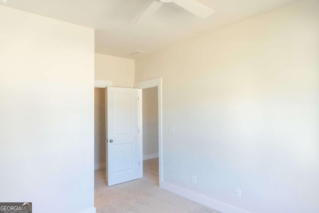 spare room with baseboards, a ceiling fan, and light carpet