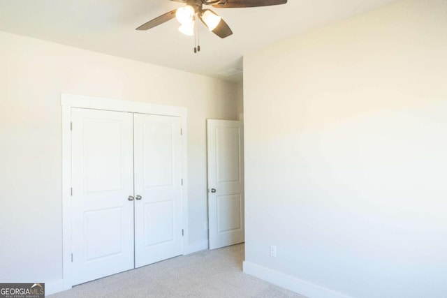 unfurnished bedroom with baseboards, a ceiling fan, a closet, and light colored carpet