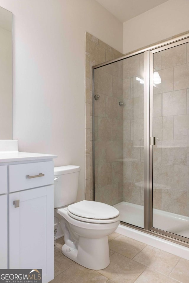 full bathroom with tile patterned floors, vanity, toilet, and a stall shower