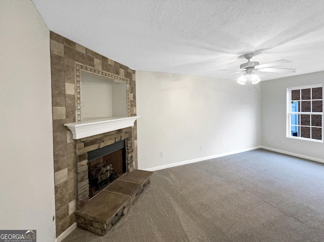 unfurnished living room with ceiling fan, a stone fireplace, a textured ceiling, and carpet floors