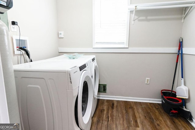 clothes washing area with dark wood-type flooring and washer and clothes dryer