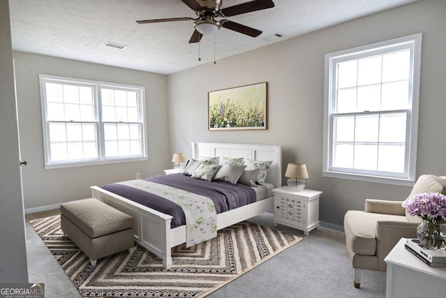 carpeted bedroom with multiple windows, a textured ceiling, and ceiling fan