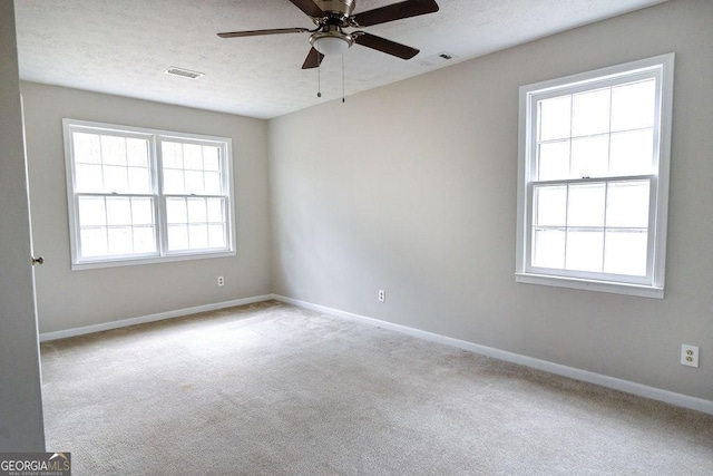 carpeted spare room with ceiling fan, a textured ceiling, and a healthy amount of sunlight