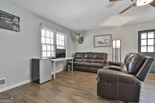 living room with a textured ceiling, ceiling fan, and dark hardwood / wood-style flooring