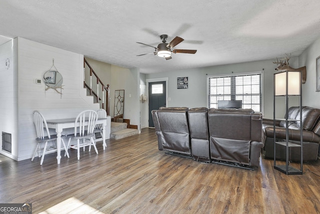 living room featuring a textured ceiling, dark wood-type flooring, and ceiling fan