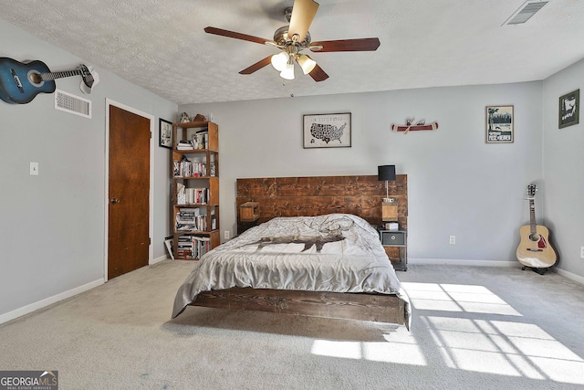 bedroom with ceiling fan, light carpet, and a textured ceiling