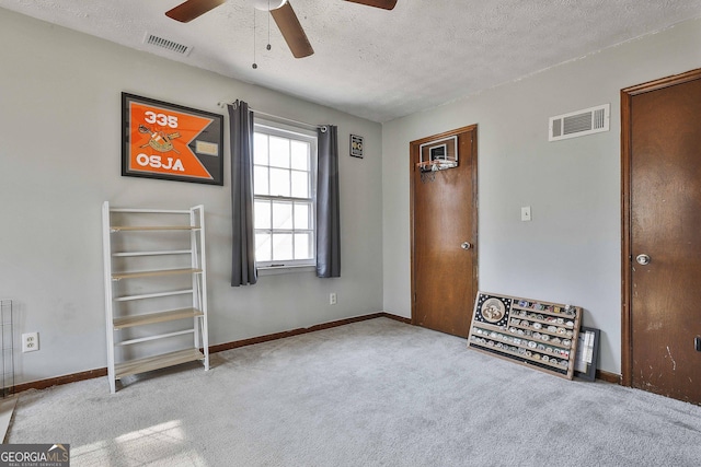 unfurnished bedroom with a textured ceiling, light carpet, and ceiling fan