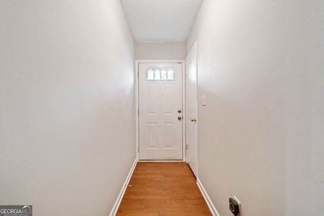 doorway with light hardwood / wood-style floors and a textured ceiling