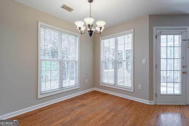 unfurnished dining area featuring plenty of natural light, wood finished floors, and visible vents